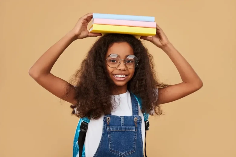 girl with big glasses, holding books on top of her head