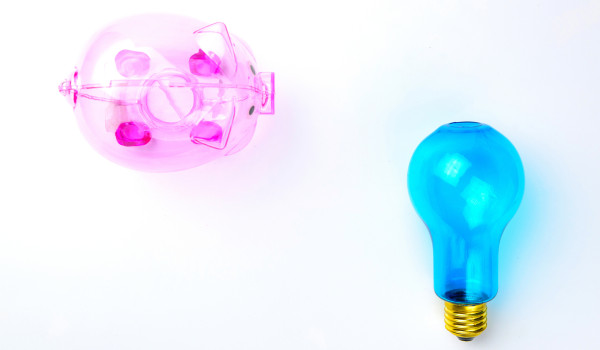 Transparent pink piggy bank and blue lightbulb
