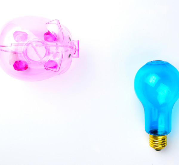 Transparent pink piggy bank and blue lightbulb