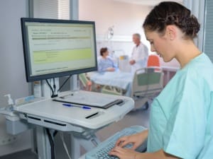 a picture of a female healthcare worker on an computer in a healthcare setting.