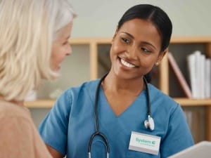A picture of a healthcare worker talking to a patient with an electronic device.