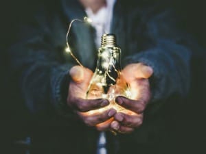 A picture of a lightbulb in someone's hand to represent clean energy.