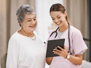 A picture of a female healthcare worker showing a patient an electronic device.
