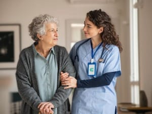 A picture of a healthcare professional linking arms with an elderly patient.