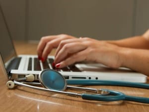A picture of a female healthcare professional looking at data on a laptop.