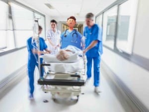 A picture of a Healthcare professionals pushing a patient in bed within a NHS hospital setting. 
