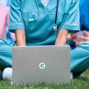 A healthcare worker using a laptop with a System C logo.