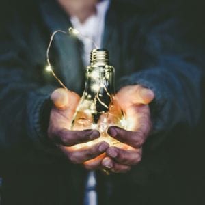 A person holding a lightbulb signalling healthcare innovation.