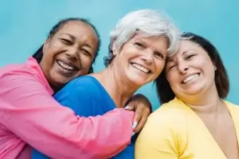 3 woman smiling and embracing with each other.