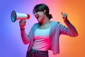 A woman shouting into a megaphone with a multi-coloured background.