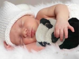 A baby cuddling a BadgerNet teddy.
