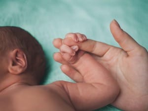 An image of a new-born holding hands with the parent/carer.