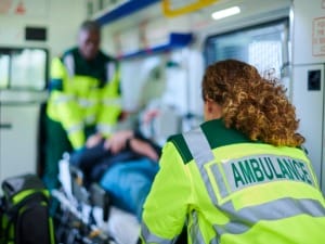 An image of two paramedics taking care of a patient inside an ambulance.