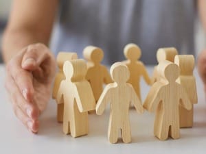 An image of a social worker with her hands around a circle of wooden people shaped figures.