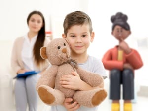 A picture of a young child stood Infront of a female social worker and a social care System C character.