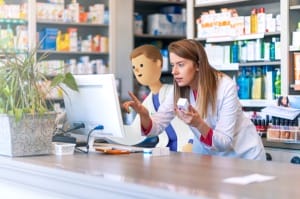 An image of a pharmacist and a System C character at a Pharmacy counter looking at a pharmacy system.