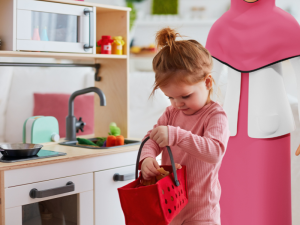 A young girl playing with a wooden kitchen set.